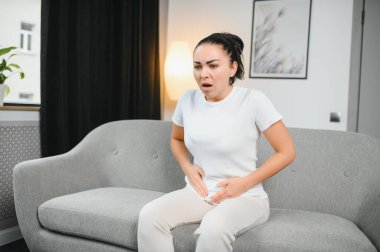 Aylık adet, adet döngüsü günü, genç bir kadın, karın ağrısı çeken bir kadın, adet öncesi, karın ağrısı ya da karın ağrısı çekiyor. Vücuttaki sağlık sorunu iltihaplandı