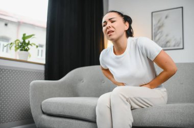 Aylık adet, adet döngüsü günü, genç bir kadın, karın ağrısı çeken bir kadın, adet öncesi, karın ağrısı ya da karın ağrısı çekiyor. Vücuttaki sağlık sorunu iltihaplandı