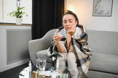 Grip ve grip. Hasta kadın üşütmüş, hasta olmuş. Battaniyeyle kaplanmış, burnunu silen ve termometreye bakan sağlıksız güzel bir kız. Sağlık hizmetleri kavramı