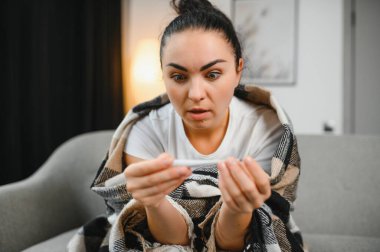 Grip ve grip. Hasta kadın üşütmüş, hasta olmuş. Battaniyeyle kaplanmış, burnunu silen ve termometreye bakan sağlıksız güzel bir kız. Sağlık hizmetleri kavramı