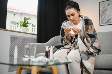 Grip ve grip. Hasta kadın üşütmüş, hasta olmuş. Battaniyeyle kaplanmış, burnunu silen ve termometreye bakan sağlıksız güzel bir kız. Sağlık hizmetleri kavramı