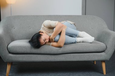 Genç bir kadın yatakta yatıyor ve jinekolojik sorunları, adet sancısı, mide ağrısı ya da karın ağrısı çekiyor. Adet dönemi ya da adet dönemi