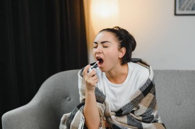 evde kanepede otururken püskürtme boğaz hasta genç kadın sıcak giysiler