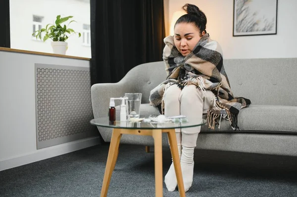 Hasta kadın. Flu. kadın üşüttü. Dokuların içine hapşırmak. Baş ağrısı. Virüs. İlaçlar. Kanepede oturan, başı ağrıyan hasta kadın.