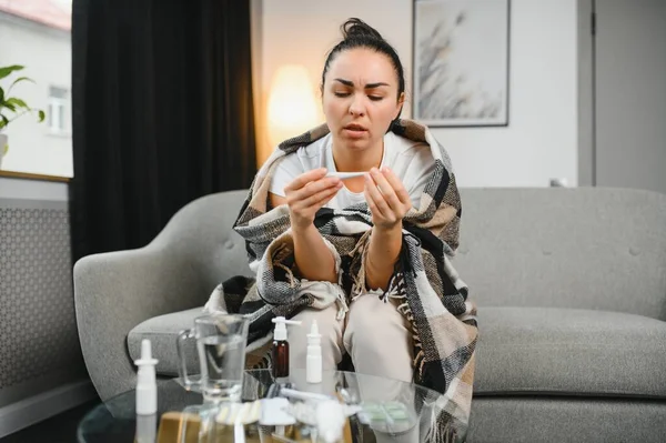 Hasta kadın. Flu. kadın üşüttü. Dokuların içine hapşırmak. Baş ağrısı. Virüs. İlaçlar. Kanepede oturan, başı ağrıyan hasta kadın.