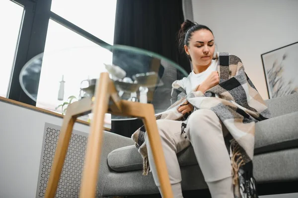 Hasta kadın. Flu. kadın üşüttü. Dokuların içine hapşırmak. Baş ağrısı. Virüs. İlaçlar. Kanepede oturan, başı ağrıyan hasta kadın.
