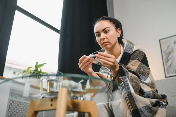 Hasta kadın. Flu. kadın üşüttü. Dokuların içine hapşırmak. Baş ağrısı. Virüs. İlaçlar. Kanepede oturan, başı ağrıyan hasta kadın.