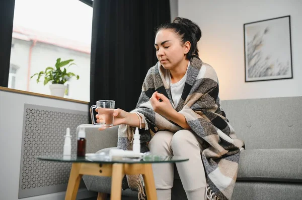 Hasta kadın. Flu. kadın üşüttü. Dokuların içine hapşırmak. Baş ağrısı. Virüs. İlaçlar. Kanepede oturan, başı ağrıyan hasta kadın.