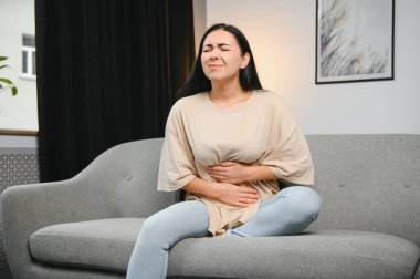 Adet sancısı, midesi ağrıyan bir kadın. Evde adet sancısı, endometriyozis, sistit ve idrar sistemindeki diğer hastalıklar.