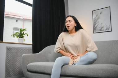 Adet sancısı, midesi ağrıyan bir kadın. Evde adet sancısı, endometriyozis, sistit ve idrar sistemindeki diğer hastalıklar.