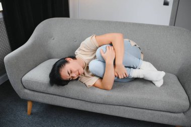 Aylık adet, adet döngüsü günü, genç bir kadın, karın ağrısı çeken bir kadın, adet öncesi, karın ağrısı ya da karın ağrısı çekiyor. Vücuttaki sağlık sorunu iltihaplandı