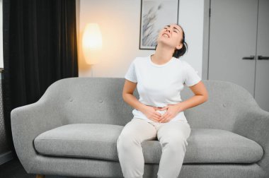 Aylık adet, adet döngüsü günü, genç bir kadın, karın ağrısı çeken bir kadın, adet öncesi, karın ağrısı ya da karın ağrısı çekiyor. Vücuttaki sağlık sorunu iltihaplandı