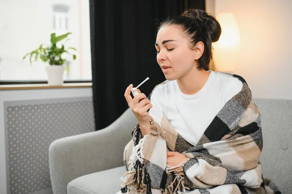 evde kanepede otururken püskürtme boğaz hasta genç kadın sıcak giysiler