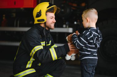 İtfaiyeci çocuğu ateşten ve dumandan kurtarmak için tutuyor. İtfaiyeciler çocukları ateşten kurtarıyor..