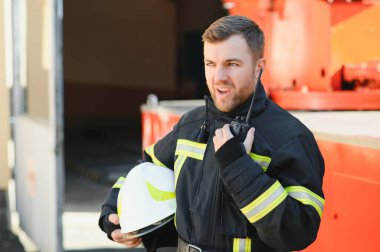 İtfaiyeci (itfaiye) eylem daimi bir firetruck yakınındaki. Acil durum Emanet. Koruma, tehlikeden kurtarmak