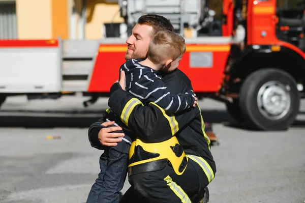 Dirty Firefighter Uniform Holding Little Saved Boy Standing Black Background — Stock Photo, Image