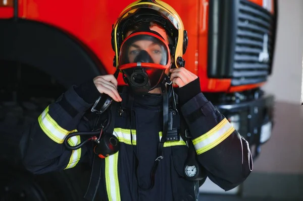 ガスマスクと消防車の近くにヘルメット消防士の写真 — ストック写真