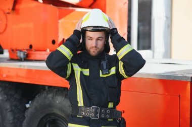 İtfaiyeci (itfaiye) eylem daimi bir firetruck yakınındaki. Acil durum Emanet. Koruma, tehlikeden kurtarmak