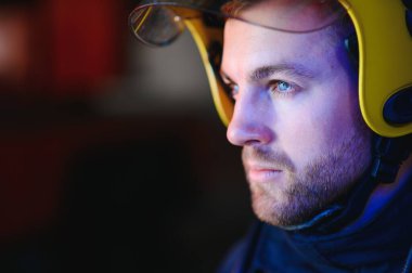 Görevdeyken itfaiyeci portresi. İtfaiye arabasının yanında gaz maskesi ve miğferi olan itfaiyeci.