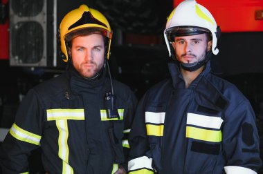 Koruyucu takım elbiseli ve kasklı iki kahraman itfaiyeci portresi.