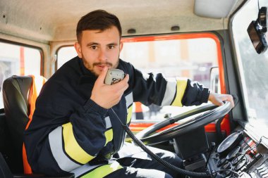 İtfaiyeci itfaiye aracı kullanırken telsiz kullanıyor.