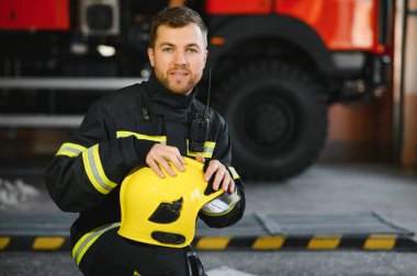 İtfaiye arabasının önünde duran bir itfaiyecinin portresi..