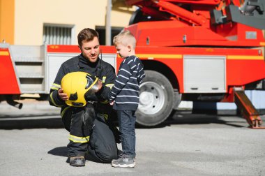 İnsanları cesur yüreklilikle tehlikeden koru. İtfaiyeci üniformalı kahraman. Güvenli çocukları dumandan koru..