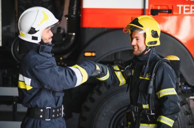 Koruyucu takım elbiseli ve kasklı iki kahraman itfaiyeci portresi.