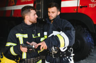 İtfaiye operasyonundaki iki itfaiyecinin portresi. Koruyucu giysili ve kasklı itfaiyeci. Eylem savaşında tablet bilgisayar kullanıyor..