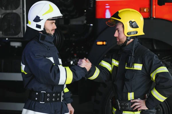 Dos Bomberos Ropa Protectora Cascos Con Camión Bomberos Apretón Manos —  Fotos de Stock