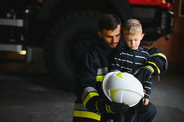 Dirty Firefighter Uniform Holding Little Saved Boy Standing Black Background — Stock Photo, Image