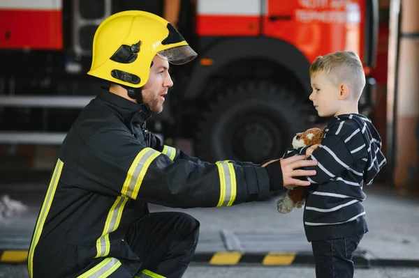 Bombeiro Sujo Uniforme Segurando Pouco Salvo Menino Fundo Preto — Fotografia de Stock