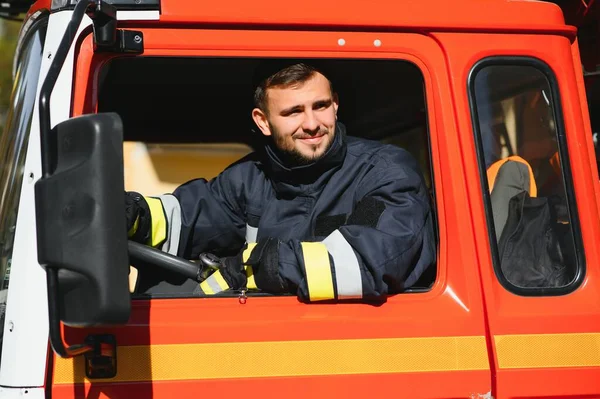 快乐的年轻消防员驾驶救火车车站的肖像 — 图库照片