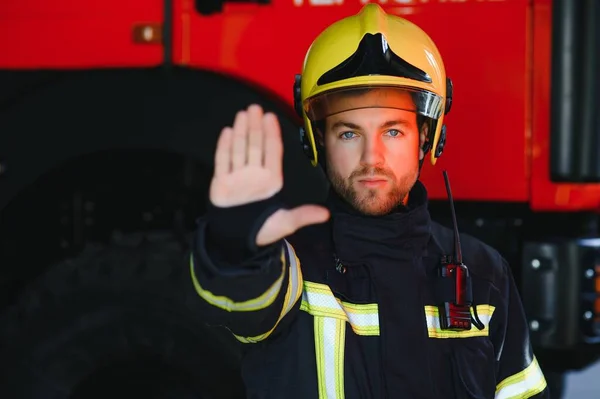 Photo of fireman with gas mask and helmet near fire engine.