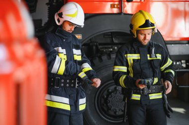 Koruyucu takım elbiseli ve kasklı iki kahraman itfaiyeci portresi.