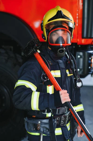 Foto Van Jonge Brandweerman Met Moker Handen Buurt Van Brandweerwagen — Stockfoto