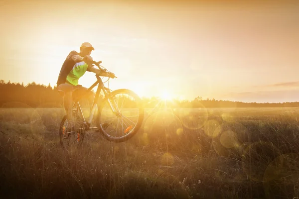 Jovem andando de bicicleta ao pôr-do-sol — Fotografia de Stock