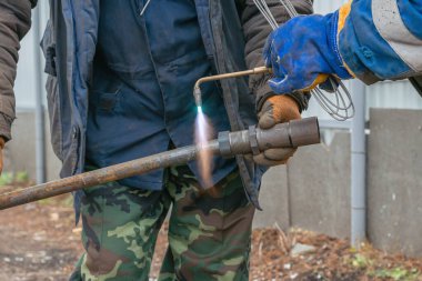 İki işçi açık hava gaz kaynakçısı kullanarak iki metal parçasına katılıyor..