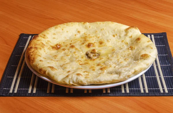 美味的国家食品 奥塞梯派 一个塞满蔬菜或肉的大扁平面包 躺在一个白盘上 — 图库照片