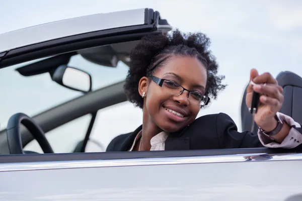 Junge schwarze Fahrerin mit Autoschlüssel am Steuer ihres neuen Autos — Stockfoto