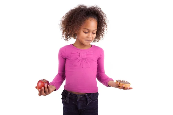 Pequena menina asiática africana hesitando entre frutas ou doces — Fotografia de Stock