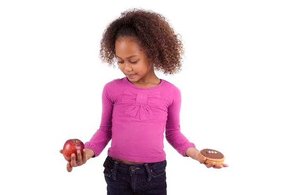 Pequena menina asiática africana hesitando entre frutas ou doces — Fotografia de Stock