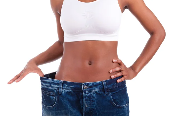 Jonge Afrikaanse vrouw in oude jeans broek na het verliezen van gewicht — Stockfoto