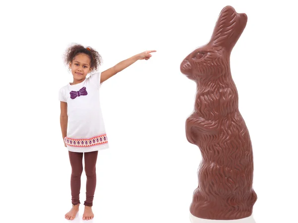 Africano menina asiática apontando um coelho de chocolate gigante — Fotografia de Stock