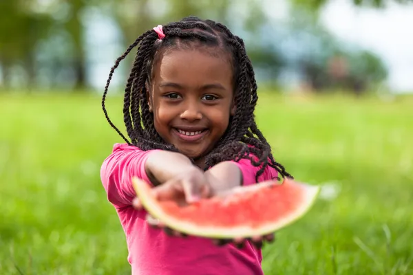 Retrato ao ar livre de uma linda jovem menina negra comendo água — Fotografia de Stock