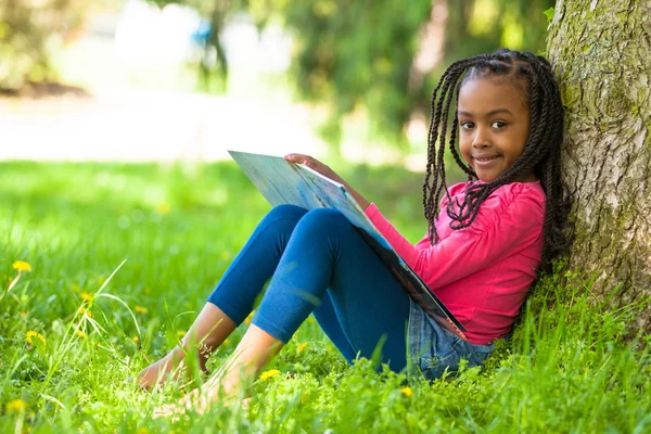 Außenporträt eines netten jungen schwarzen Mädchens beim Lesen eines Buhs — Stockfoto