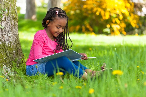 Retrato al aire libre de una linda niña negra leyendo un boo — Foto de Stock