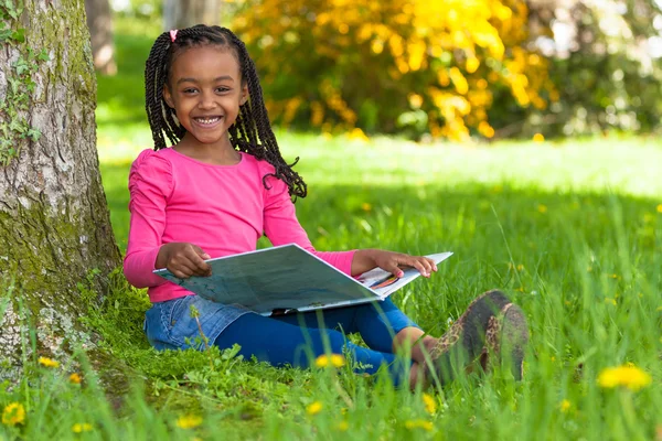 Außenporträt eines netten jungen schwarzen Mädchens beim Lesen eines Buhs — Stockfoto