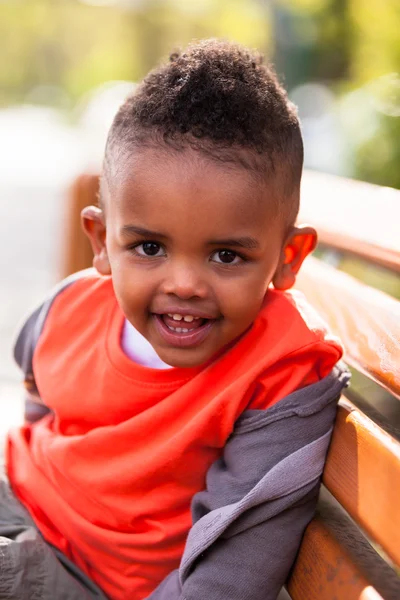 Außenporträt eines netten kleinen schwarzen Jungen, der auf einem B sitzt — Stockfoto