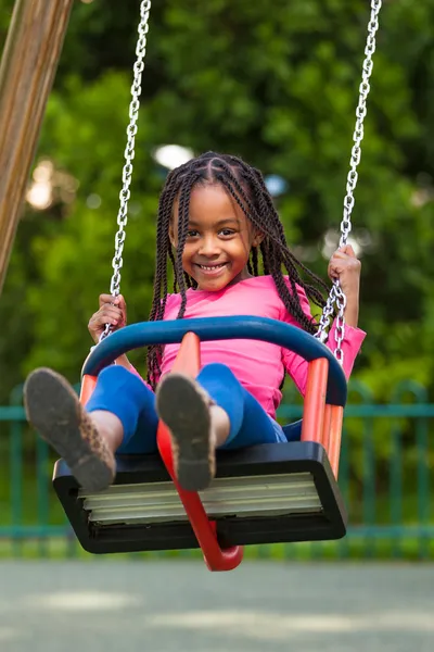 Outdoor portrait of a cute young black girl playing with a swin Stock Picture